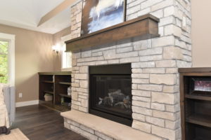 Stone surround gas fireplace with stone hearth and custom wood mantle