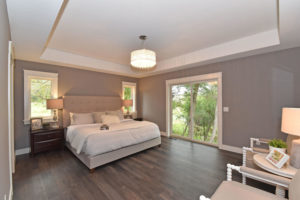 Master suite bedroom with warm tones and tray ceiling