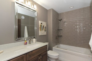 Bathroom with grey subway tile and stained vanity